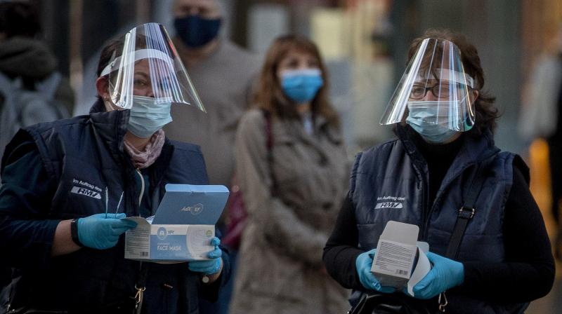 Women working for the regional public transport company distribute face masks in the main train station in Frankfurt, Germany, (AP)