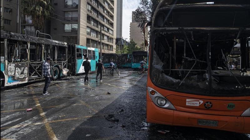 Buses that were set alight by demonstrators during last night's protests stand on a street in Santiago, Chile, Saturday, Oct. 19, 2019. (Image: AP) Buses that were set alight by demonstrators during last night's protests stand on a street in Santiago, Chile, Saturday, Oct. 19, 2019. (Image: AP)