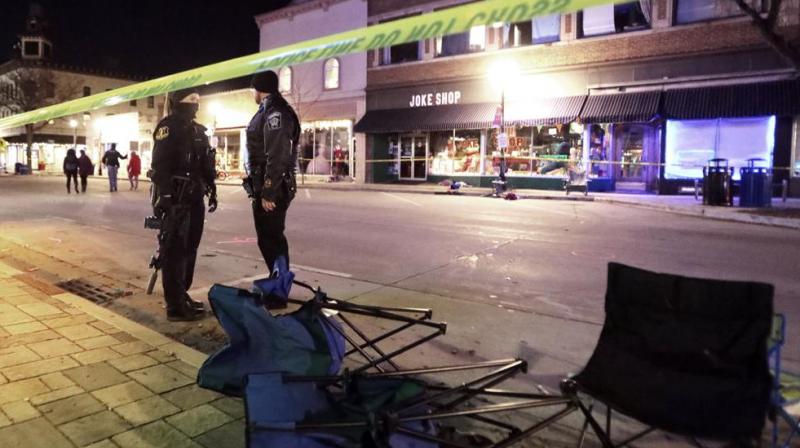 Police stand near toppled chairs lining W. Main St. in downtown Waukesha, Wis., after an SUV drove into a parade of Christmas marchers, Sunday, Nov. 21, 2021. (John Hart/Wisconsin State Journal via AP)