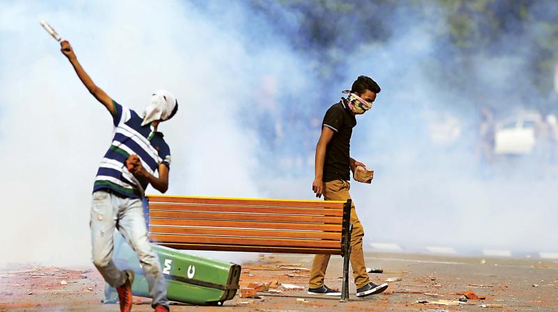 A student throws a teargas canister towards security personnel in central Srinagar’s Lal Chowk on Tuesday. The police fired into a crowd of stone-throwing students in Kashmir as violence in the region intensified. (Photo: AFP) A student throws a teargas canister towards security personnel in central Srinagar’s Lal Chowk on Tuesday. The police fired into a crowd of stone-throwing students in Kashmir as violence in the region intensified. (Photo: AFP)
