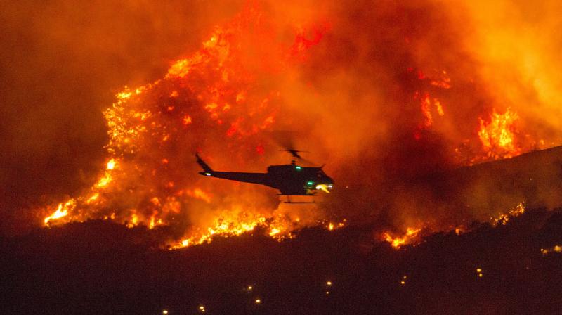 Three fast-spreading California wildfires sent people fleeing Saturday, with one trapping campers at a reservoir in the Sierra National Forest, as a brutal heat wave pushed temperatures into triple digits in many parts of state. (AP)