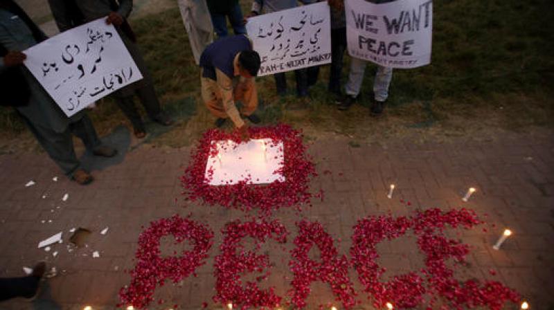 A Christian adjusts a candle next to wording 'Peace' drawn with rose petals during a candlelight vigil for the victims of an overnight attack on the Quetta Police Training Academy, in Islamabad, Pakistan. (Photo: AP) A Christian adjusts a candle next to wording 'Peace' drawn with rose petals during a candlelight vigil for the victims of an overnight attack on the Quetta Police Training Academy, in Islamabad, Pakistan. (Photo: AP)