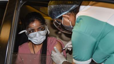 A health worker administers a dose of the COVID-19 vaccine to a woman at a drive-through vaccination camp at Select City Walk mall in New Delhi. (Photo: PTI)