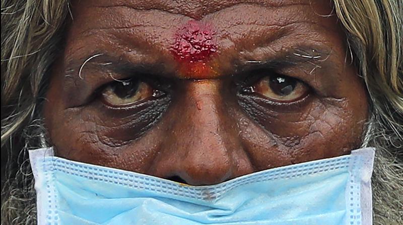 A farmer wearing a face mask listens to a speaker during an anti-government protest in Bengaluru. (AP) A farmer wearing a face mask listens to a speaker during an anti-government protest in Bengaluru. (AP)