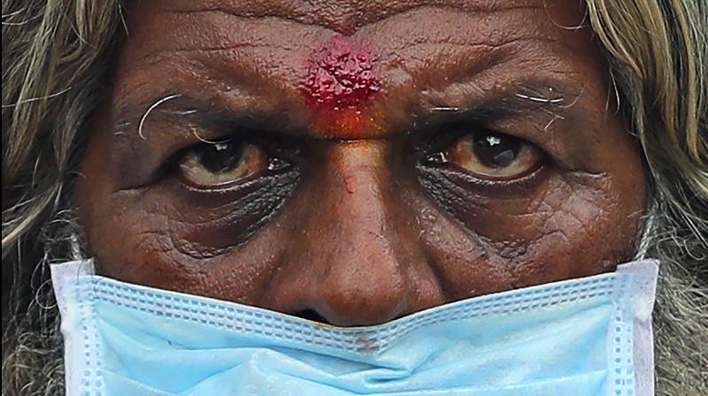 A farmer wearing a face mask listens to a speaker during an anti-government protest in Bengaluru. (AP)