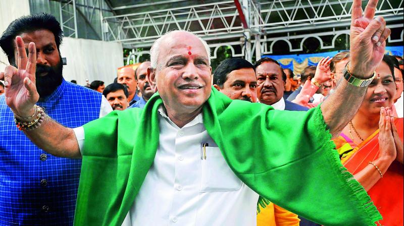 BJP leader B. S. Yeddyurappa flashes the victory sign as he arrives to take oath as Chief Minister of Karnataka in Bengaluru on Thursday