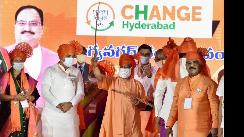 Uttar Pradesh Chief Minister Yogi Adityanath, flanked by BJP Telangana leaders, holds a sword during a public meeting, ahead of GHMC elections in Hyderabad, Saturday, November 28 (PTI)