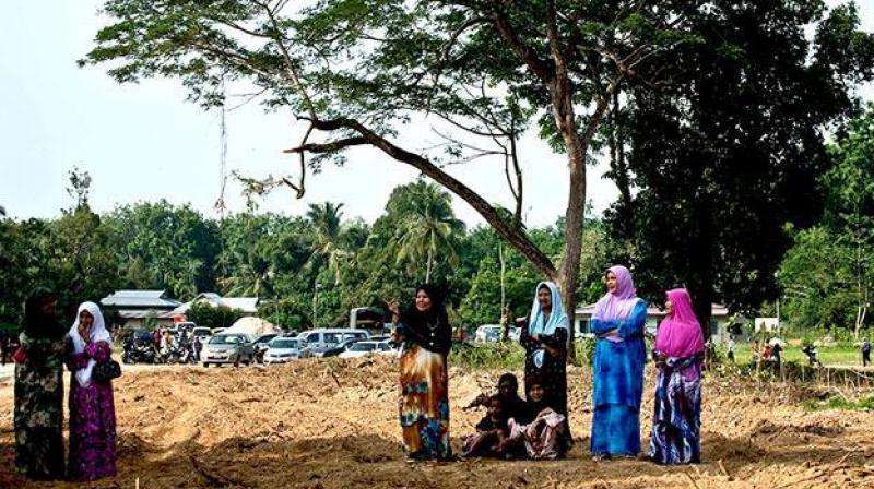 Local Malaysian women watch preparations for the re burial of remains believed to be those of ethnic Rohingya found at human trafficking camps. (Photo: AFP) Local Malaysian women watch preparations for the re burial of remains believed to be those of ethnic Rohingya found at human trafficking camps. (Photo: AFP)