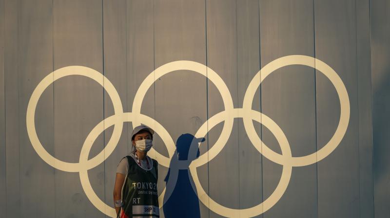 A volunteer walks past the Olympic rings ahead of the 2020 Summer Olympics in Tokyo on Thursday. (Photo: AP)