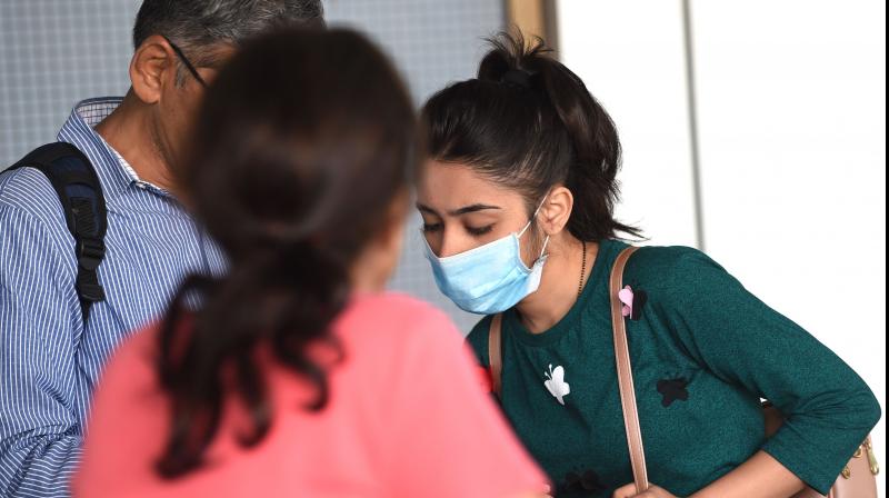 A passenger wearing a facemask as a preventive measure against the spread of the COVID-19 coronavirus outbreak, interacts with her relatives upon her arrival at the Sardar Vallabhbhai Patel international airport in Ahmedabad. PTI photo