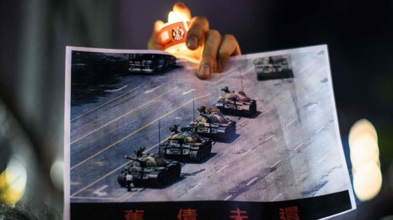 A man holds a poster of the famous Tank Man standing in front of Chinese military tanks at Tiananmen Square in Beijing on June 5, 1989, a day after a crackdown, in which the military killed hundreds of unarmed protesters. On June 4, 2020, tens of thousands of people across Hong Kong lit candles and chanted democracy slogans on June 4 to commemorate Chinas deadly Tiananmen crackdown, defying a ban against gathering as tensions seethed over a planned new security law. (Photo | AFP)