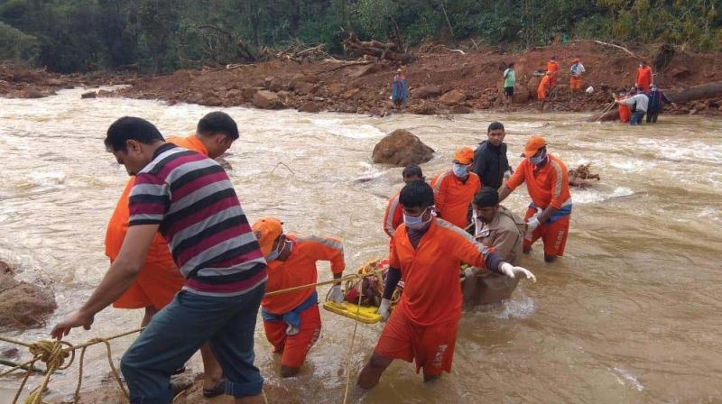 NDRF personnel shift a body found buried in the slush near Madikeri on Saturday (Image: DC) NDRF personnel shift a body found buried in the slush near Madikeri on Saturday (Image: DC)