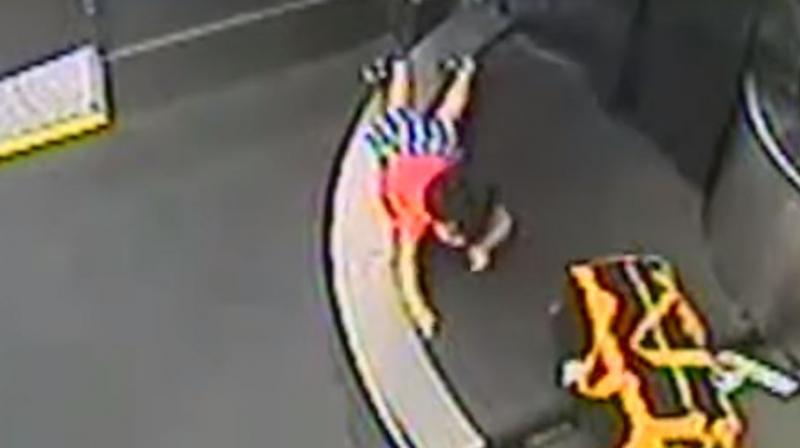 Video then shows him crawling over bags, trying to avoid being pulled through a large screening machine that resembles a darkened cave above the conveyor belt. (Photo: Screengrab) Video then shows him crawling over bags, trying to avoid being pulled through a large screening machine that resembles a darkened cave above the conveyor belt. (Photo: Screengrab)