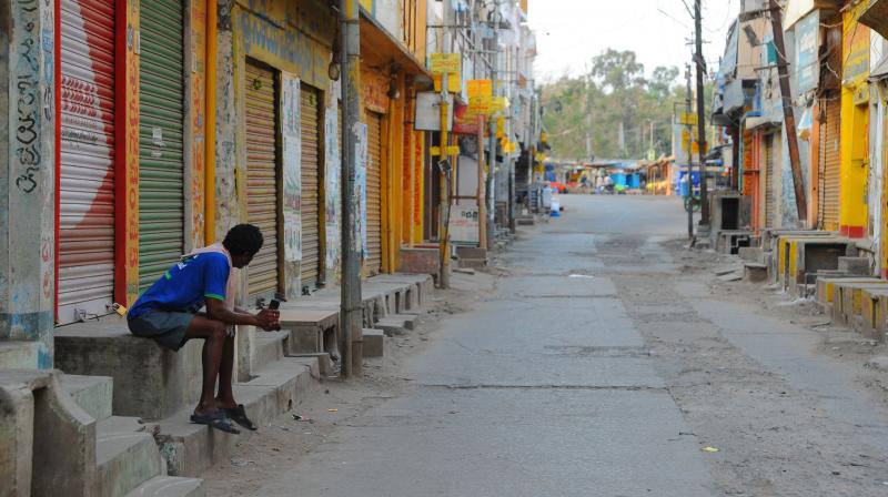 A lone worker surveys an empty market street in Guntur, Andhra Pradesh. (DC Photo: Tejo Roy) A lone worker surveys an empty market street in Guntur, Andhra Pradesh. (DC Photo: Tejo Roy)