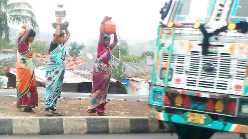 Women of Ganeshnagar cross the NH-44 to return to their village after collecting water in pots from Sainagar village in Gudihathnoor mandal in Adilabad district. Women of Ganeshnagar cross the NH-44 to return to their village after collecting water in pots from Sainagar village in Gudihathnoor mandal in Adilabad district.