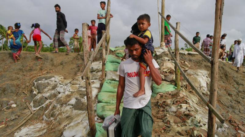 A Rohingya man carrying his son and belongings walks through a broken road after crossing the Bangladeshi border at Shah Porir Deep, in Teknak, Bangladesh. (Photo: AP) A Rohingya man carrying his son and belongings walks through a broken road after crossing the Bangladeshi border at Shah Porir Deep, in Teknak, Bangladesh. (Photo: AP)