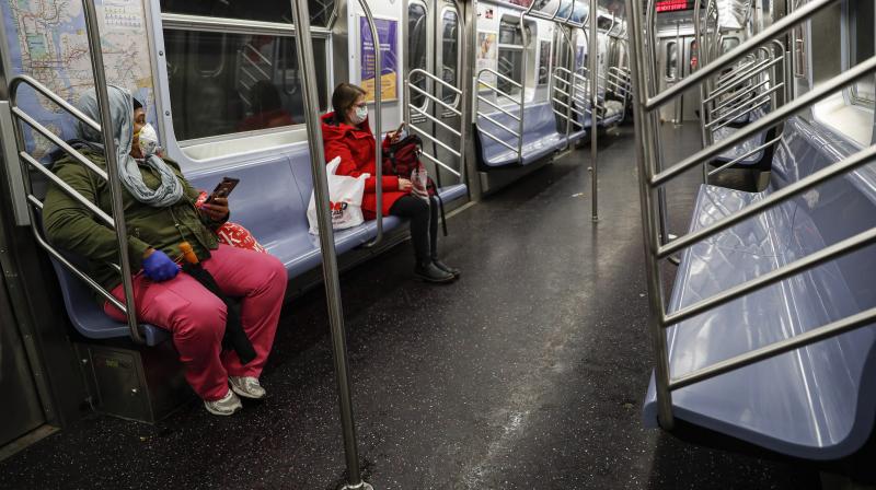 Subway riders wear protective masks and gloves on a sparsely populated car during morning hours due to COVID-19 concerns that are driving down ridership in New York. AP Photo