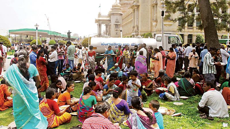 A file photo of people having lunch on the premises of Vidhana Soudha during distribution of free ration to BPL card holders under Anna Bhagya scheme, in Bengaluru. (Photo:KPN) A file photo of people having lunch on the premises of Vidhana Soudha during distribution of free ration to BPL card holders under Anna Bhagya scheme, in Bengaluru. (Photo:KPN)