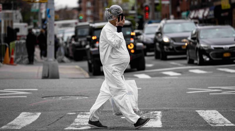 A pregnant woman wearing a hazmat suit and a mask walks in the streets in the Elmhurst neighbourhood of Queens on Monday in New York City. (AFP)