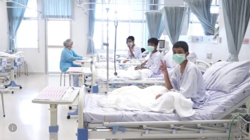 Footage shows them behind quarantine glass in bed wearing smocks and facemasks, flashing peace signs and doing the traditional 'wai' greeting. (Photo: AP) Footage shows them behind quarantine glass in bed wearing smocks and facemasks, flashing peace signs and doing the traditional 'wai' greeting. (Photo: AP)