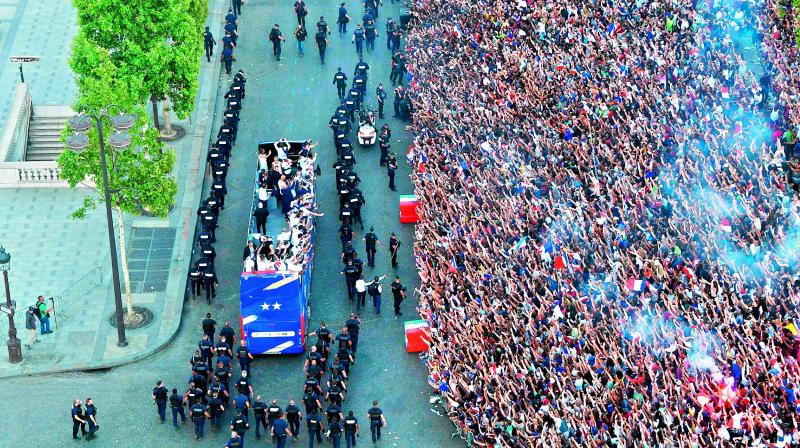 Fans greet the France national football team players as they celebrate on the roof of a bus while they parade down the Champs-Elysee avenue in Paris. (Photo: AFP) Fans greet the France national football team players as they celebrate on the roof of a bus while they parade down the Champs-Elysee avenue in Paris. (Photo: AFP)
