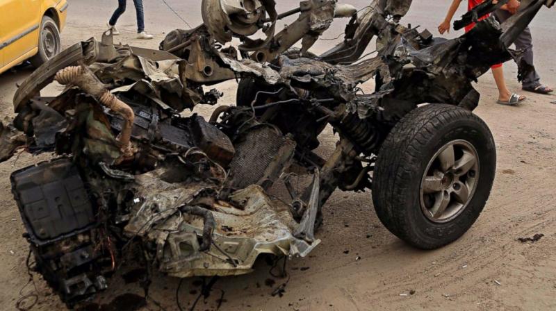 Civilians pass a destroyed car in the a car bomb explosion in southwestern Baghdad, Iraq. (Photo: AP) Civilians pass a destroyed car in the a car bomb explosion in southwestern Baghdad, Iraq. (Photo: AP)