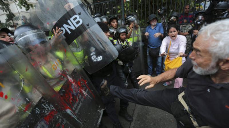 An anti-government protester kicks at riot police blocking a march of elders against President Nicolas Maduro in Caracas, Venezuela. (Photo: AP) An anti-government protester kicks at riot police blocking a march of elders against President Nicolas Maduro in Caracas, Venezuela. (Photo: AP)