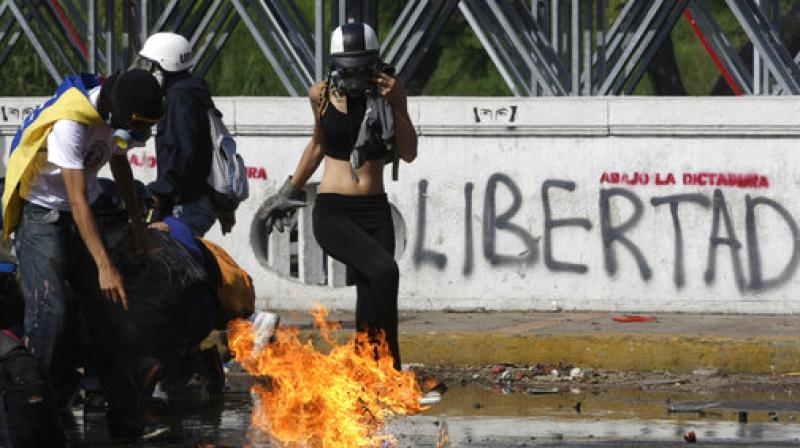 Protesters take cover from fire thrown by riot police during a march towards the Ombudsman's Office in protest of President Nicolas Maduro in Caracas, Venezuela. (Photo: AP) Protesters take cover from fire thrown by riot police during a march towards the Ombudsman's Office in protest of President Nicolas Maduro in Caracas, Venezuela. (Photo: AP)