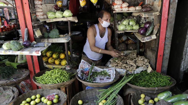 A vegetable vendor wears face mask as a precaution against COVID-19 in Mumbai, India. AP Photo