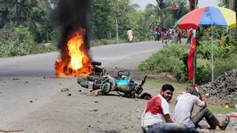 People injured in poll violence sit by the side of a road as a vehicle is set on fire by locals during Panchayat polls, in Nadia district of West Bengal on Monday. (Photo: PTI) People injured in poll violence sit by the side of a road as a vehicle is set on fire by locals during Panchayat polls, in Nadia district of West Bengal on Monday. (Photo: PTI)