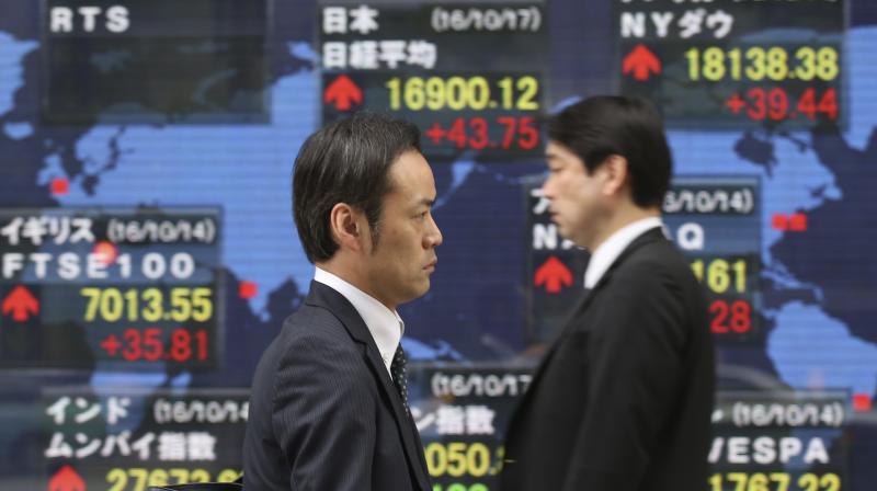 People walk by an electronic stock board of a securities firm in Tokyo. (Photo:AP) People walk by an electronic stock board of a securities firm in Tokyo. (Photo:AP)