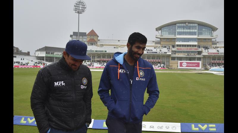 Indias Jasprit Bumrah (right) and a member of team support staff walk back towards their dressing room after taking a stroll around the field after rain delayed start of the fifth day of first test cricket match between England and India at Trent Bridge in Nottingham, England, on Sunday. -- AP