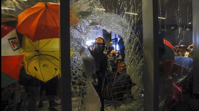 A small group, mostly students wearing hard hats and masks, used a metal trolley, poles and pieces of scaffolding to hack through reinforced glass and charge at the government compound. (Photo: AP) A small group, mostly students wearing hard hats and masks, used a metal trolley, poles and pieces of scaffolding to hack through reinforced glass and charge at the government compound. (Photo: AP)