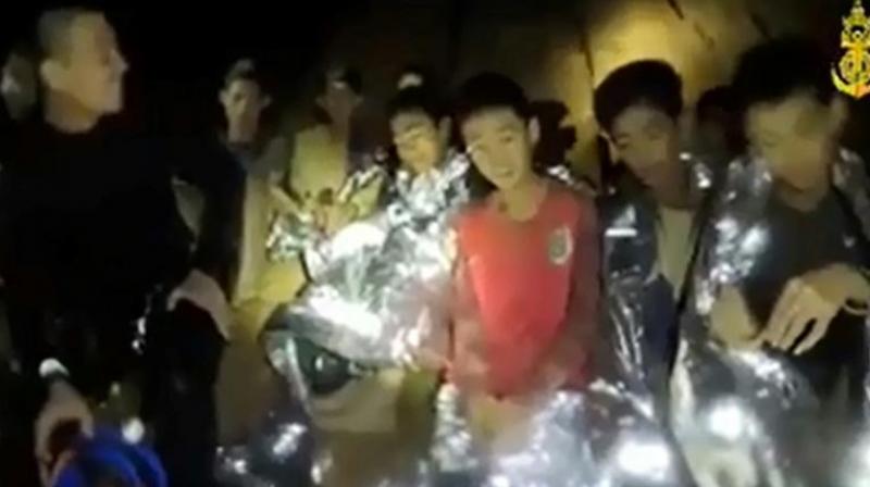 Several of the boys in the frame are wearing protective foil blankets and are accompanied by a smiling diver in a wetsuit. (Photo: AFP) Several of the boys in the frame are wearing protective foil blankets and are accompanied by a smiling diver in a wetsuit. (Photo: AFP)