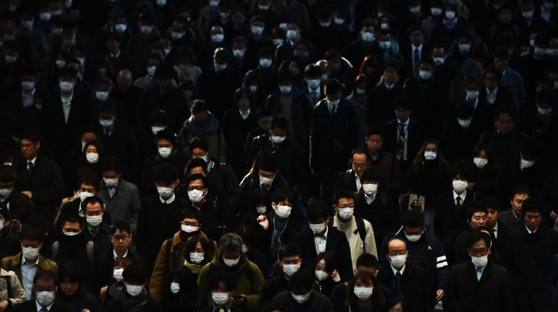 Mask-clad commuters make their way to work during the morning rush hour at Shinagawa train station in Tokyo, Japan. AFP Photo