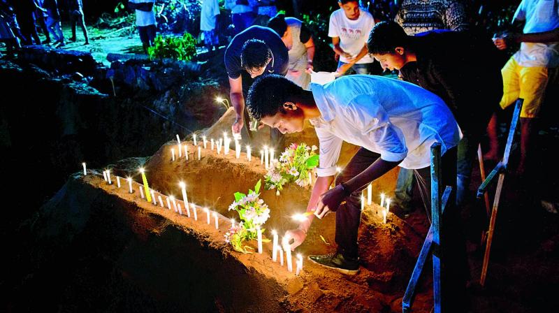Relatives light candles after burial of three victims of the same family, who died at Easter Sunday bomb blast at St. Sebastian Church in Negombo, Sri Lanka on Monday. (Image: AP) Relatives light candles after burial of three victims of the same family, who died at Easter Sunday bomb blast at St. Sebastian Church in Negombo, Sri Lanka on Monday. (Image: AP)