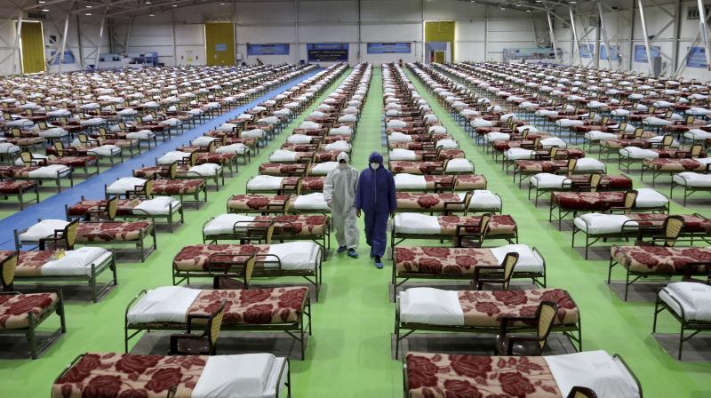 People in protective clothing walk past rows of beds at a temporary 2,000-bed hospital for COVID-19 coronavirus patients set up by the Iranian army at the international exhibition center in northern Tehran, Iran. AP Photo People in protective clothing walk past rows of beds at a temporary 2,000-bed hospital for COVID-19 coronavirus patients set up by the Iranian army at the international exhibition center in northern Tehran, Iran. AP Photo