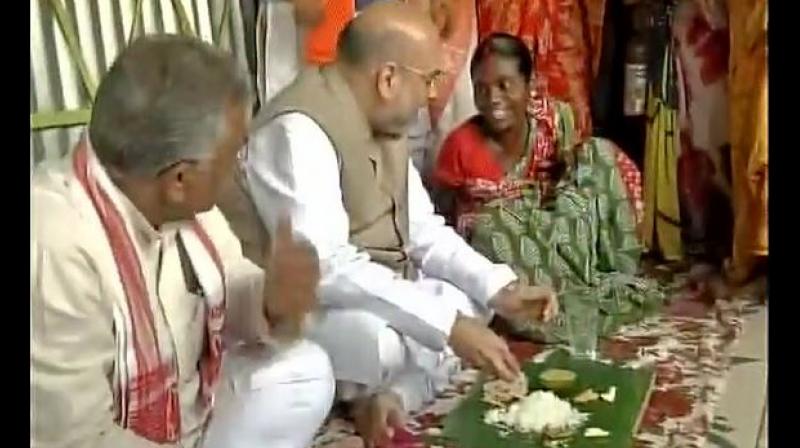 BJP President Amit Shah eating lunch at the house of a tribal family in Naxalbari, West Bengal. (Photo: ANI/Twitter) BJP President Amit Shah eating lunch at the house of a tribal family in Naxalbari, West Bengal. (Photo: ANI/Twitter)