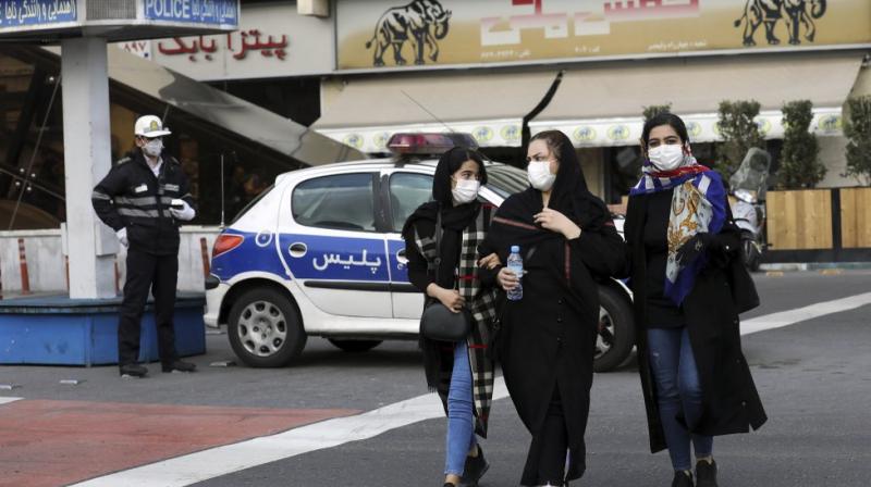 A policeman and pedestrians wear masks to help guard against the Coronavirus, in downtown Tehran, Iran. AP Photo