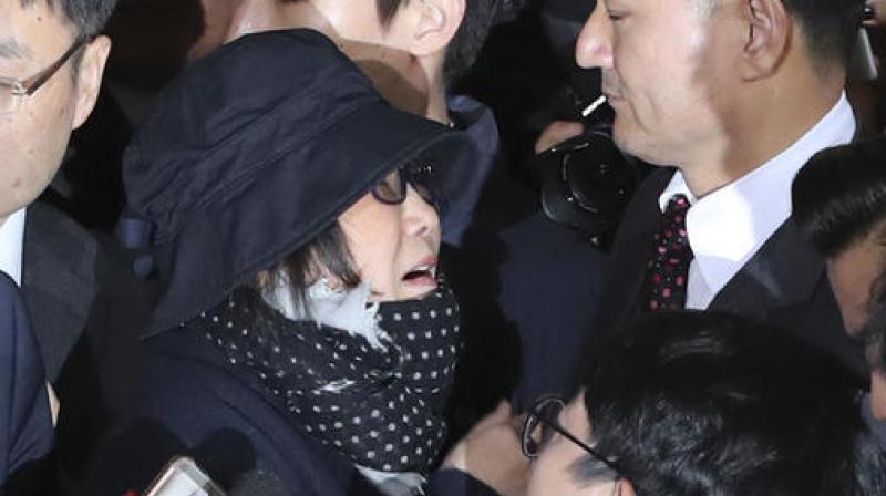 Choi, wearing a bucket hat and scarf, her hand pressed to her mouth, was nearly knocked off her feet several times as she tried to walk through a massive crowd of media. (Photo: AP) Choi, wearing a bucket hat and scarf, her hand pressed to her mouth, was nearly knocked off her feet several times as she tried to walk through a massive crowd of media. (Photo: AP)
