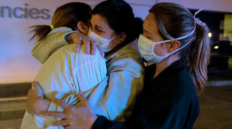 Healthcare workers dealing with the new coronavirus crisis in Spain, hug each other as they are cheered on by people outside La Fe hospital in Valencia. AFP Photo Healthcare workers dealing with the new coronavirus crisis in Spain, hug each other as they are cheered on by people outside La Fe hospital in Valencia. AFP Photo