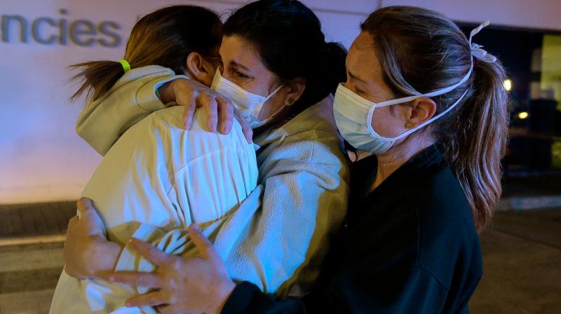 Healthcare workers dealing with the new coronavirus crisis in Spain, hug each other as they are cheered on by people outside La Fe hospital in Valencia. AFP Photo