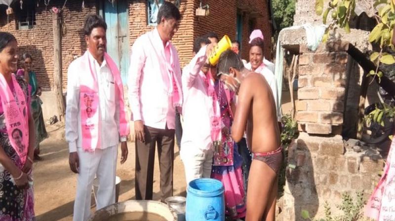 TRS leader Koram Kanakaiah from Yellandu constituency was seen helping a person take bath by pouring water on his head with a mug. (Photo: ANI) TRS leader Koram Kanakaiah from Yellandu constituency was seen helping a person take bath by pouring water on his head with a mug. (Photo: ANI)