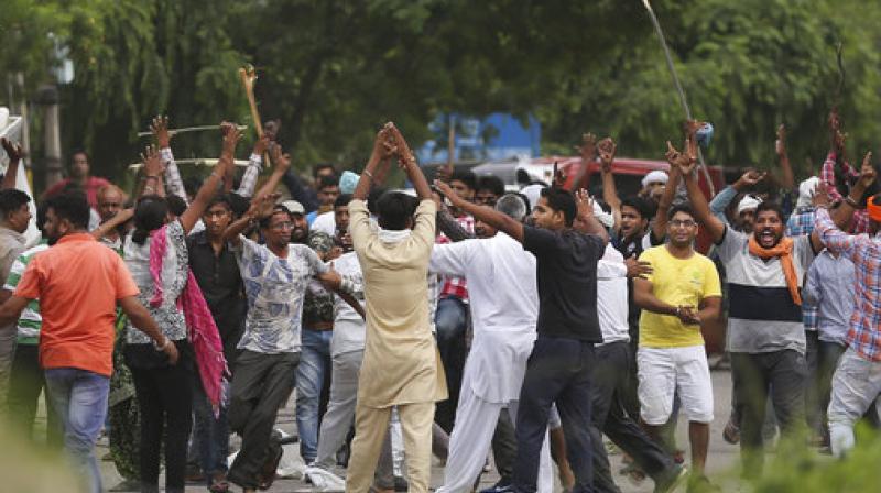 Supporters, back toward camera, try to calm other supporters of the Dera Sacha Sauda sect near an Indian court in Panchkula, on Friday. (Photo: PTI) Supporters, back toward camera, try to calm other supporters of the Dera Sacha Sauda sect near an Indian court in Panchkula, on Friday. (Photo: PTI)