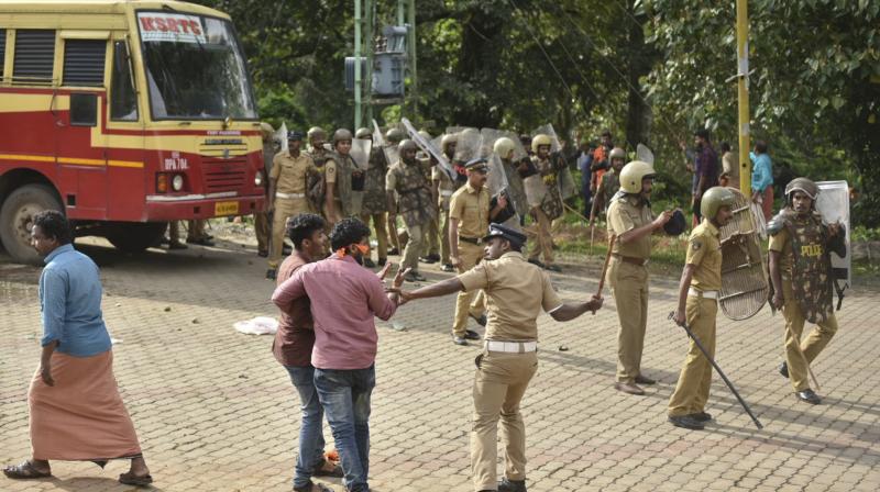 A policeman charges his baton at protestors who tried to block women of menstruating age from going to the Sabarimala temple at Nilackal, a base camp on way to the mountain shrine in Kerala. (Photo: AP) A policeman charges his baton at protestors who tried to block women of menstruating age from going to the Sabarimala temple at Nilackal, a base camp on way to the mountain shrine in Kerala. (Photo: AP)