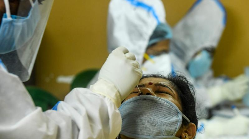 A health worker collects a swab sample from a resident of a housing society for COVID-19 coronavirus test during a door-to-door testing programme. AFP Photo