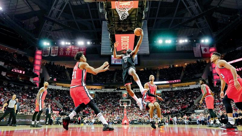 Houston Rockets James Harden (13) goes up for a shot as Portland Trail Blazers Hassan Whiteside (21) and Rodney Hood (5) look on during their NBA game. AP Photo