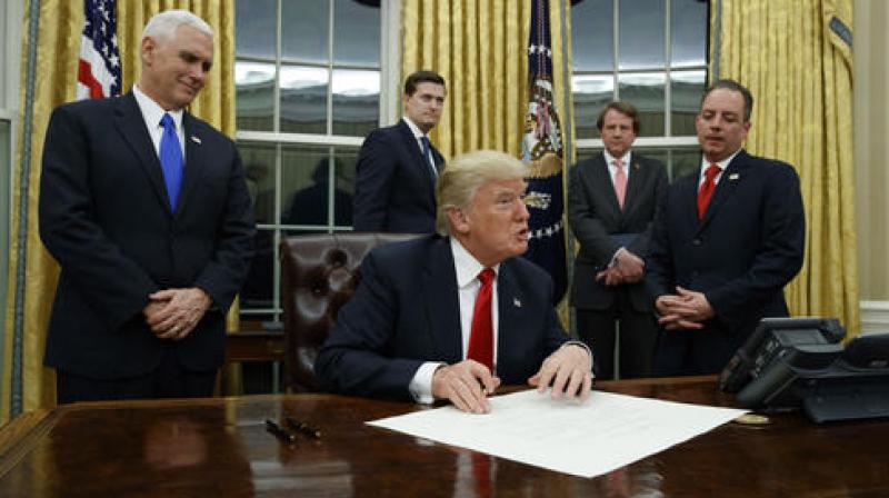 Vice President Mike Pence watches at left as President Donald Trump prepares to sign his first executive order, Friday, Jan. 20, 2017, in the Oval Office of the White House in Washington. Vice President Mike Pence watches at left as President Donald Trump prepares to sign his first executive order, Friday, Jan. 20, 2017, in the Oval Office of the White House in Washington.
