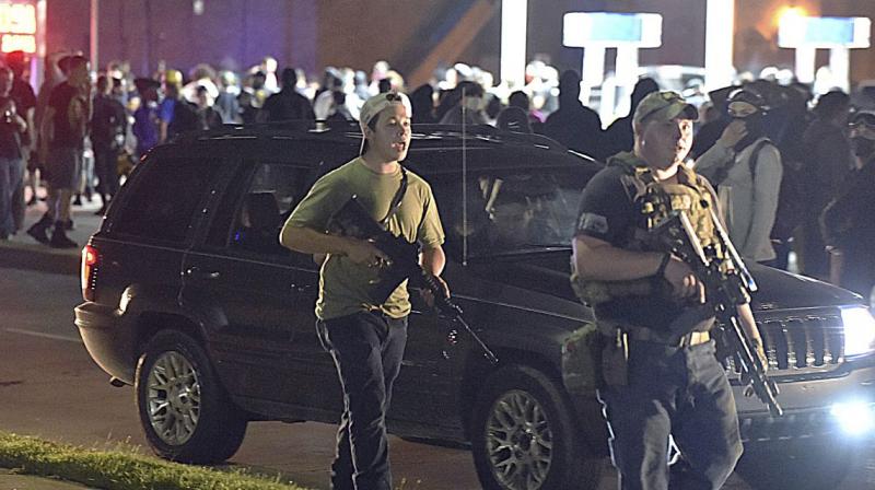 Kyle Rittenhouse (left, with backwards cap) walks along Sheridan Road in Kenosha, Wisconsin, on Tuesday, with another armed civilian. (via AP)