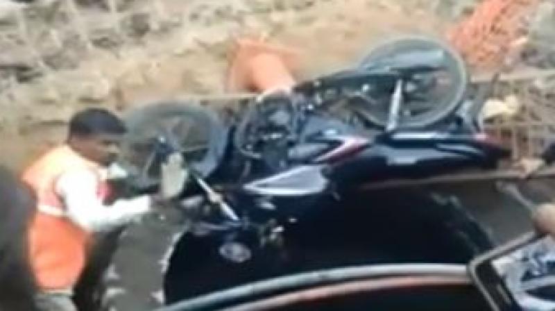A video, which has gone viral, shows the bike lying next to the manhole, while passersby have gathered around the manhole with some trying to lower a thick rope and a ladder, in a bid to rescue the man. (Photo: SCreengrab) A video, which has gone viral, shows the bike lying next to the manhole, while passersby have gathered around the manhole with some trying to lower a thick rope and a ladder, in a bid to rescue the man. (Photo: SCreengrab)